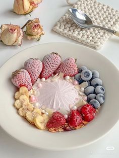 a white plate topped with fruit and veggies on top of a table next to flowers