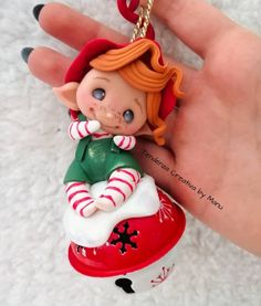 a hand holding a small christmas ornament in it's palm with a little elf on it