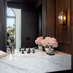 a bathroom sink with marble counter top next to a large mirror and flowers on it