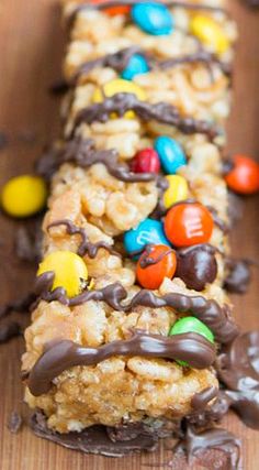 some kind of candy bar that is on a wooden table with chocolate and m & m candies