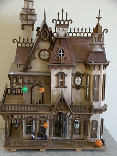 a toy house with lots of windows and decorations on the front, sitting on a table