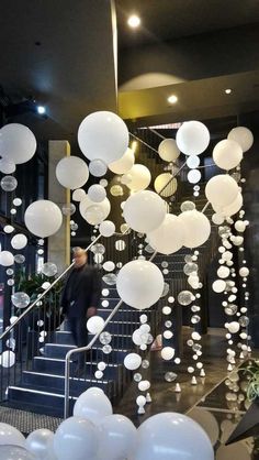 white balloons are floating from the ceiling in front of a staircase with stairs and balconies