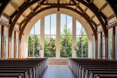 the inside of a church with rows of pews and large windows looking out on trees