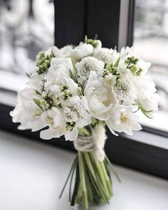 a bouquet of white flowers sitting on top of a window sill