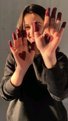 a girl with her hands in the shape of hearts, holding up two fingers and smiling