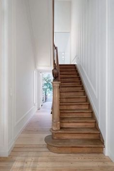 an empty hallway with wooden stairs and white walls