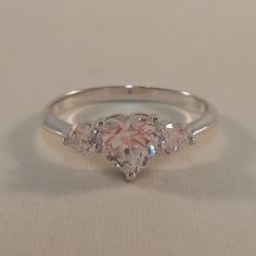 three stone diamond ring on white surface with light colored stones in the middle and bottom