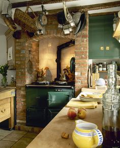 an old fashioned kitchen with green cabinets and pots hanging from the ceiling, along with other appliances