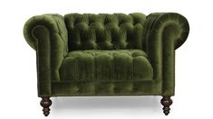 a green velvet chair with wooden legs and buttons on the armrests, in front of a white background