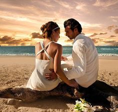 a man and woman sitting on top of a beach