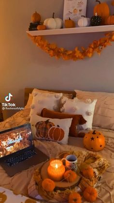 a laptop computer sitting on top of a bed next to pumpkins and other decorations