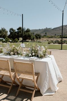 the table is set with white flowers and greenery