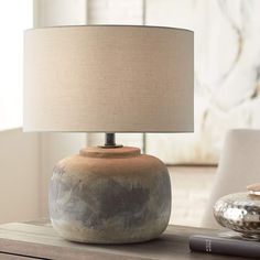 a table lamp sitting on top of a wooden table next to a book and glass vase