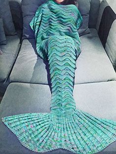 a woman is sitting on a couch with a knitted mermaid tail in front of her