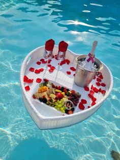 a small boat floating in the water with fruit and drinks on it's tray