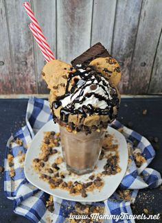 an ice cream sundae with chocolate chip cookies and whipped cream on top, sitting on a blue checkered napkin