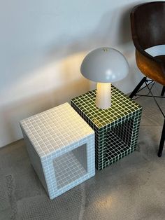 a lamp sitting on top of two different colored boxes next to a chair and table