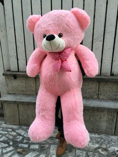 a large pink teddy bear sitting on top of a bench