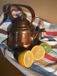 a tea kettle and two lemons on a towel with a striped cloth around it