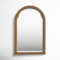 an arched mirror hanging on the wall next to a white wall with a wooden frame