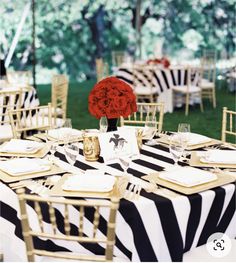 a black and white striped table cloth with red roses in a vase on the center