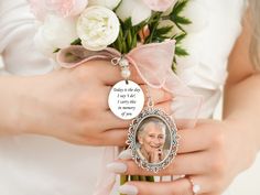 a woman holding a bouquet of flowers with a photo on it's charm attached to her wrist