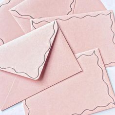 four pink envelopes with white paper on them