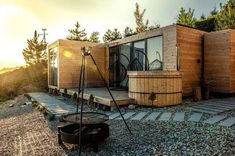 an outdoor hot tub in the middle of a gravel area next to a wooden building