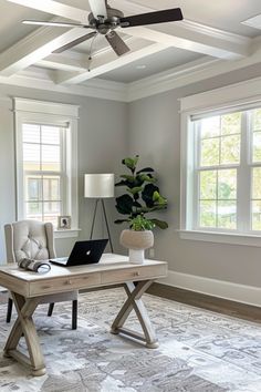 a living room with a laptop on a table and a ceiling fan in the corner