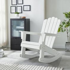 a white rocking chair sitting on top of a rug next to a potted plant