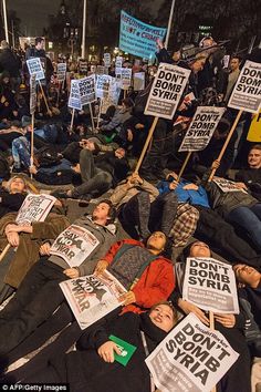 people laying on the ground holding signs and placares in front of them at night