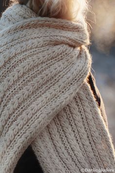 a close up of a person wearing a sweater with a scarf around it's neck