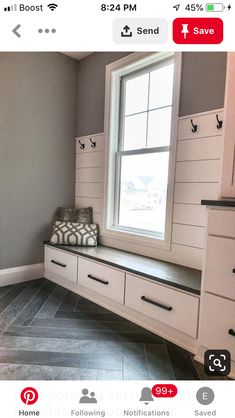 a window seat in the corner of a room with gray tile flooring and white cabinets