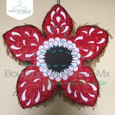 a red and white paper flower hanging on a wall