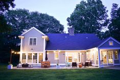 a house that is lit up at night with lights on the front porch and patio