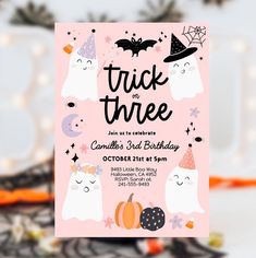 a pink halloween birthday party card with ghostes and pumpkins on it, in front of a white background