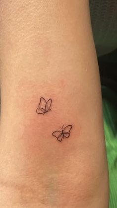 two small butterflies on the back of a woman's leg, one is black and white