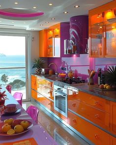 an orange and pink kitchen with the ocean in the backgrounnd, along with fruit on the table