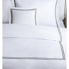 a bed with white sheets and black trimmings