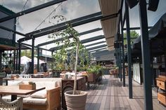 an outdoor seating area with tables and chairs on the deck, surrounded by potted plants