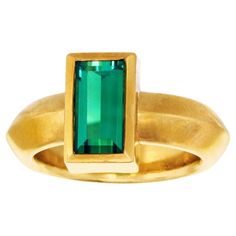 Circa 1970s, 18k, Swiss. This chic seventies ring features a stunning deep blue-green tourmaline in a hyper-modern 18k yellow gold setting. Superbly made and easy to wear, this vibrant ring is in excellent condition. Remark: "Intense color makes the look pop." SIZE: 6 WEIGHT: 13.0 grams STONES: 1.75 carat tourmaline HALLMARKS: 750 for 18k and maker's mark H STOCK NUMBER: 24888 Jewelry acquired from this dealer must delight you. Purchases may be returned for any reason for a period of 7 days. Modern Tourmaline Emerald Ring, Modernist Multi-stone Ring, Tourmaline Ring 1stdibs, Yellow Gold Tourmaline Cabochon Ring, Luxury Tourmaline Cabochon Rings, Yellow Gold Setting, Tourmaline Ring, Green Tourmaline, Intense Colors