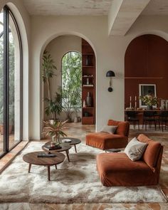 a living room filled with lots of furniture next to tall glass windows and doors leading outside