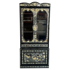 an ornate black and white cabinet with mirrors on it's sides, against a white background