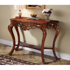 a wooden console table sitting on top of a hard wood floor next to a wall