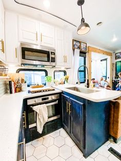 people are sitting at the kitchen counter in this modern style home with white cabinets and black appliances