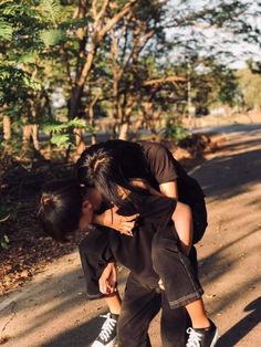 two people are kissing on the street with trees in the background