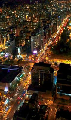 an aerial view of a city at night with lots of lights on the buildings and streets