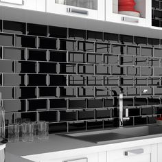 a black and white photo of a kitchen counter top with glassware on the sink