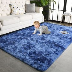 a baby crawling on a blue rug in a living room