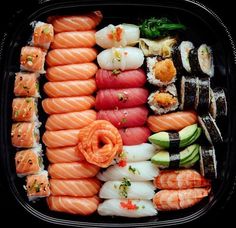 an assortment of sushi in a black container